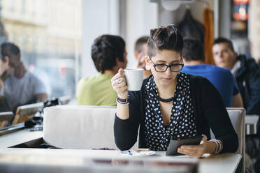 Frau mit Tablet-Computer und Kaffeetasse in einem Café - CAVF67663