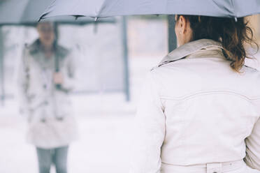 Rückansicht einer Frau mit Regenschirm in der Stadt - CAVF67671