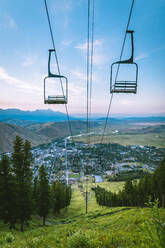 Ski lift over mountain with city in background - CAVF67678