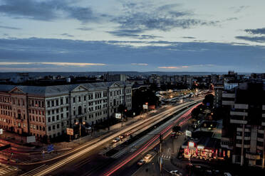 High angle view of light trails on city street against cloudy sky - CAVF67706