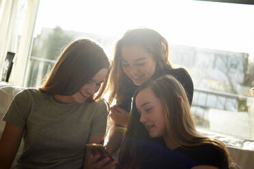 Happy female friends looking at smart phone - CAVF67715