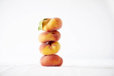 Stack of peaches against white background - CAVF67841