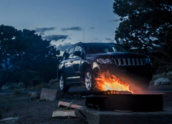 Fire pit by off-road vehicle against sky at dusk - CAVF67848