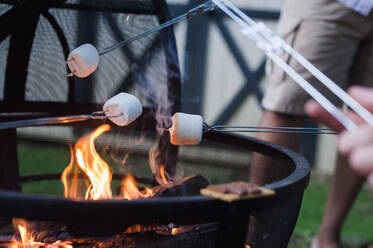 Mittelteil eines Mannes, der am Lagerfeuer im Hof Marshmallows röstet - CAVF67861