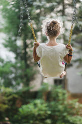 Rear view of carefree girl swinging at park - CAVF67865