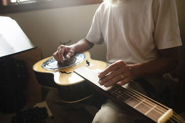 Mittelteil eines älteren Mannes, der zu Hause Gitarre lernt - CAVF67881