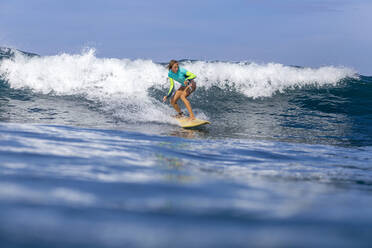 Woman surfing in sea against sky on sunny day - CAVF67890