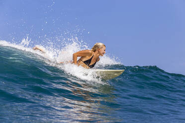 Confident woman surfing in sea against sky - CAVF67891