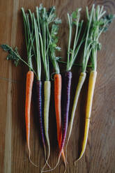 High angle view of colorful carrots on wooden table - CAVF68041