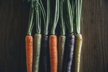 Close-up of colorful carrots on wooden table - CAVF68042