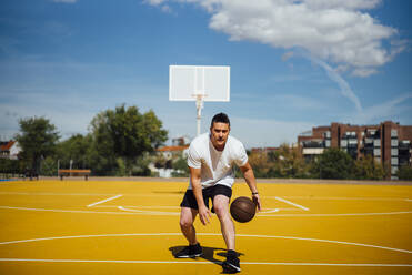 Mann spielt Basketball auf gelbem Platz, dribbelnd - OCMF00845