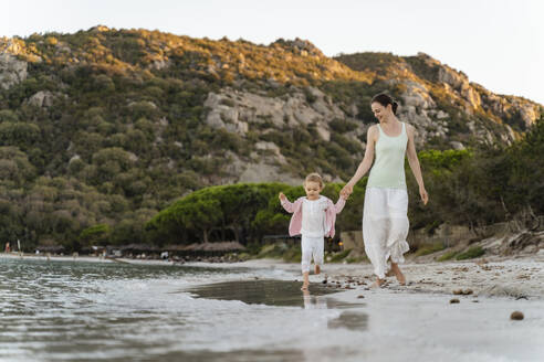 Happy mother walking with daughter on the beach - DIGF08725