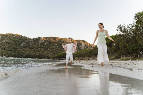 Glückliche Mutter, die mit ihrer Tochter am Strand spazieren geht - DIGF08726