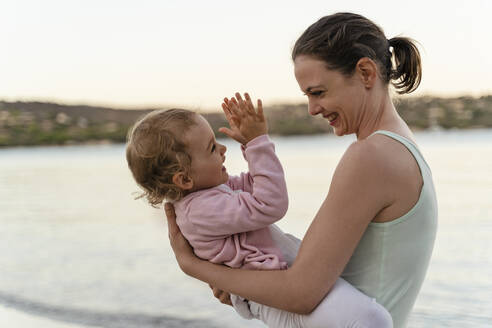 Happy mother carrying her daughter on the beach - DIGF08736