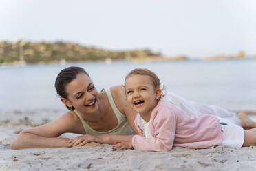 Happy mother with daughter lying on the beach - DIGF08742