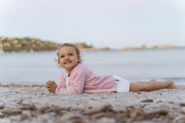 Happy cute toddler girl lying on the beach - DIGF08743