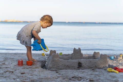 Cute toddler girl building a sand castle on the beach stock photo