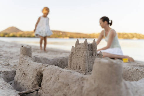 Sand castle and mother with daughter on the beach - DIGF08751