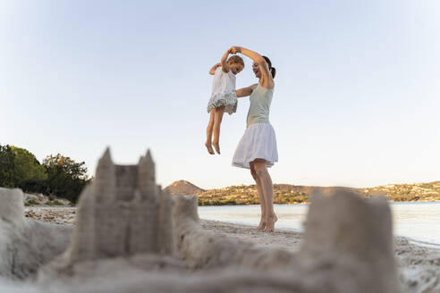 Sand castle and happy mother with daughter on the beach - DIGF08752
