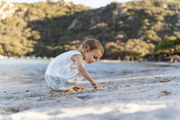 Cute toddler girl playing on the beach - DIGF08793