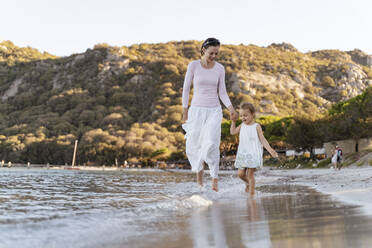 Happy mother with daughter walking at the seafront - DIGF08800