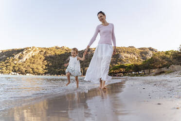 Happy mother with daughter walking at the seafront - DIGF08801