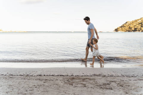 Happy father walking with daughter on the beach stock photo