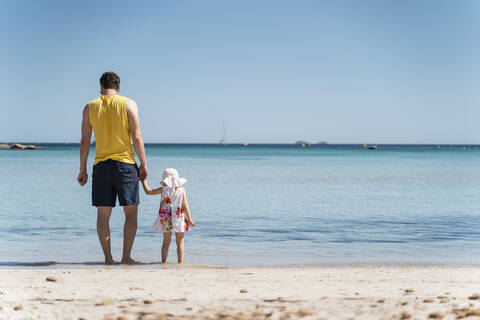 Rückansicht von Vater mit Tochter am Strand stehend, lizenzfreies Stockfoto