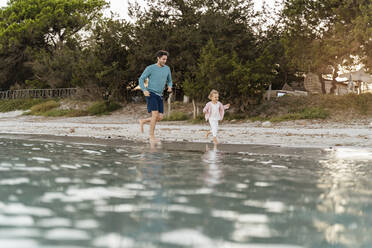 Glücklicher Vater läuft mit seiner Tochter am Meer - DIGF08814