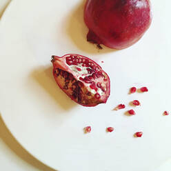 High angle view of pomegranate in white plate on table - CAVF68165