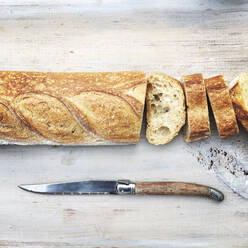 Aufgeschnittener Laib Brot mit Messer auf Holztisch - CAVF68172