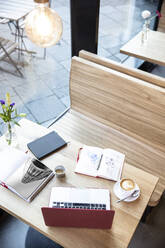 Laptop und Bücher auf einem Tisch in einem Cafe - FKF03698