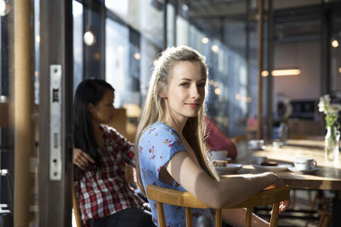 Portrait of confident woman with friends in a cafe - FKF03705