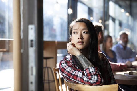 Porträt einer tätowierten Frau mit Kollegen in einem Kaffeehaus, lizenzfreies Stockfoto