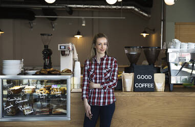 Portrait of confident woman at the counter of a cafe - FKF03709