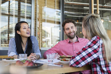 Glückliche Freunde beim Mittagessen in einem Cafe - FKF03715