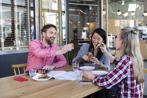 Glückliche Freunde beim Mittagessen in einem Cafe - FKF03716