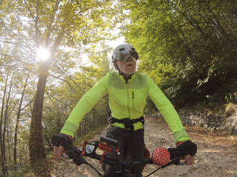 Senior man riding e-bike in nature - LAF02387