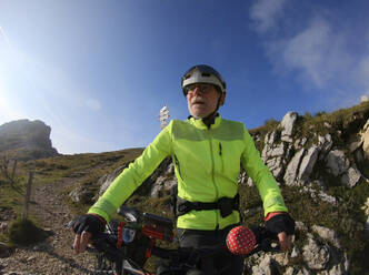 Senior man riding e-bike in nature - LAF02391