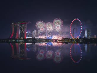 Singapore, Night firework display between Marina Bay Sands hotel and illuminated Ferris wheel - DVGF00067