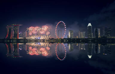 Singapore, Night firework display between Marina Bay Sands hotel and illuminated Ferris wheel - DVGF00068