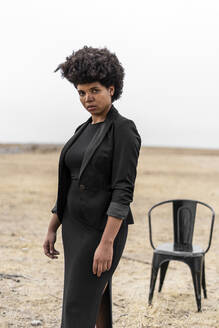 Porträt einer selbstbewussten, schwarz gekleideten jungen Frau in einer düsteren Landschaft - ERRF01915