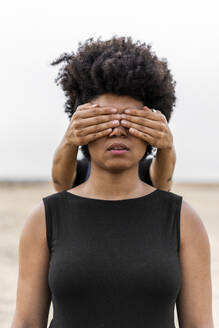 Woman's hands covering eyes of another woman - ERRF01917