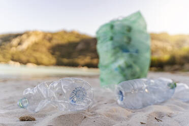 Leere Plastikflaschen und Mülleimer mit gesammelten Plastikflaschen am Strand - DIGF08820