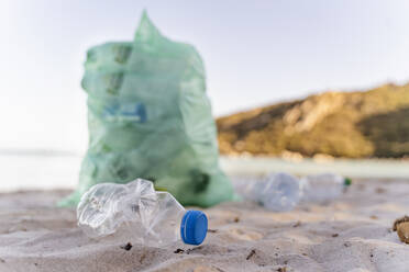 Leere Plastikflaschen und Mülleimer mit gesammelten Plastikflaschen am Strand - DIGF08821