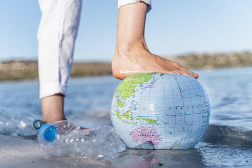 Man's foot on Earth beach ball, close-up - DIGF08822