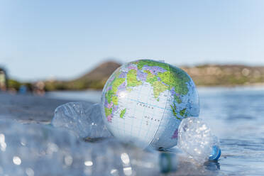 Strandball aus Erde zwischen leeren Plastikflaschen am Meeresstrand - DIGF08824