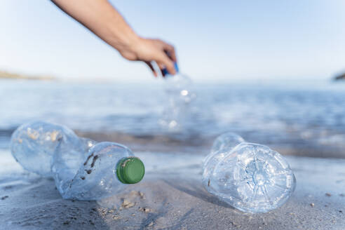 Hand collecting empty plastic bottles at seashore - DIGF08826