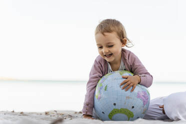 Porträt eines glücklichen kleinen Mädchens, das mit einem Strandball aus Erde spielt - DIGF08832