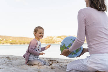 Portrait of laughing little girl playing with Earth beach ball - DIGF08836